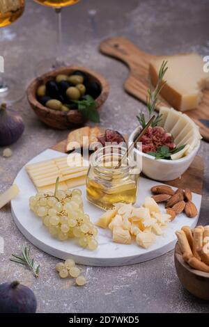 Pannello di formaggio in marmo con formaggi, noci, miele e uva Foto Stock