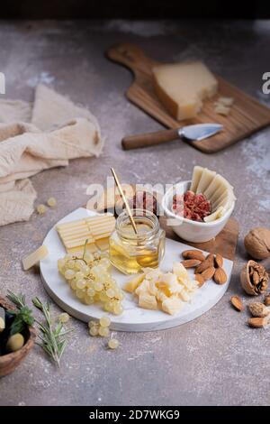 Formaggi assortiti su tavola di marmo con fichi, noci, uva e miele Foto Stock