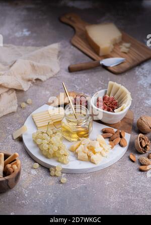 Formaggi assortiti su tavola di marmo con fichi, noci, uva e miele Foto Stock