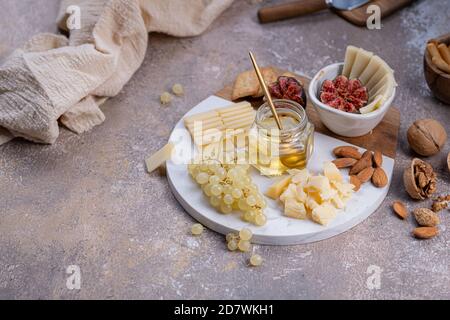 Tavola di formaggi con formaggi, noci, miele e uva, spazio copia Foto Stock