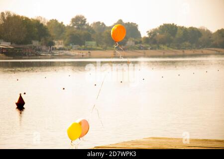 Mongolfiere di celebrazione legati su un molo su un lago al tramonto Foto Stock