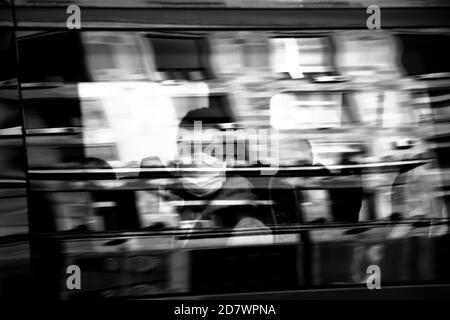 Belgrado, Serbia - 09 ottobre 2020: Persona blurry che indossa la maschera chirurgica facciale che cavalcano su un posto della finestra di un autobus di trasporto pubblico, in nero e whi Foto Stock