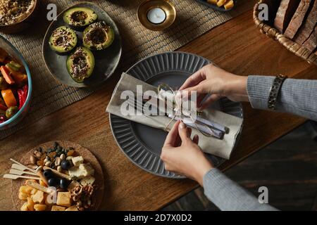 Alto angolo vicino di mani femminili legando tovaglioli e argenteria mentre decorando tavolo da cena in autunno, spazio di copia Foto Stock