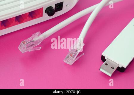 Router Internet, adattatore wi-fi USB portatile e prese per cavo Internet si trovano su uno sfondo rosa brillante. Elementi necessari per la connessione a Internet Foto Stock