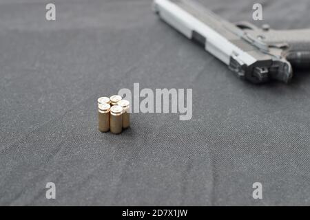 i proiettili 9mm e la pistola si trovano su un tessuto nero. Un set di articoli della gamma di tiro o un kit di auto-difesa. Conchiglie d'oro vicino alla pistola Foto Stock