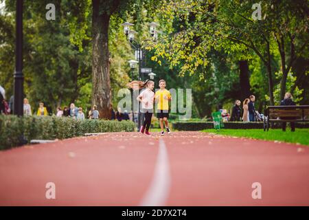 Fitness per bambini, bambini gemelli che corrono sulla pista dello stadio nel parco cittadino, allenamento e bambini che praticano uno stile di vita sano. Attività all'aperto con la corsa make Foto Stock