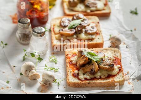 Toast croccante con funghi, formaggio e olio d'oliva su carta bianca Foto Stock
