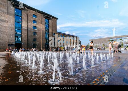 King's Cross Londra, Regno Unito, 12 luglio 2019: La gente di Granary Square gode all'aperto, fontana d'acqua Foto Stock