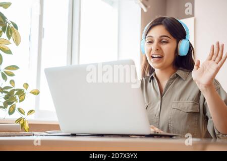 Una studentessa indiana indossa le cuffie per videochiamare con il computer portatile. Foto Stock