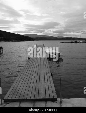 Barca ormeggiata al molo di legno il tradizionale villaggio greco porto di Agios Stefanos, Corfù, Grecia Foto Stock