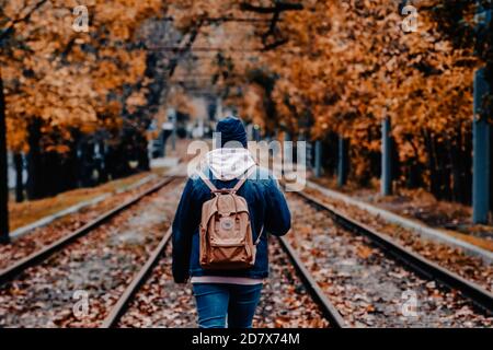 La ragazza cammina lungo le rotaie nella città d'autunno Foto Stock