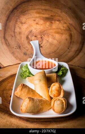 Involtini primaverili serviti con un dolce tuffo di peperoncino con un sfondo di legno Foto Stock