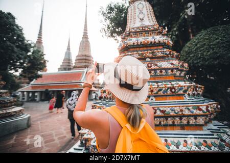 Giovane donna che scatta foto con il suo viaggio mobile in Thailandia Con il cappello che cammina a Wat Pho a Bangkok Thailandia Foto Stock