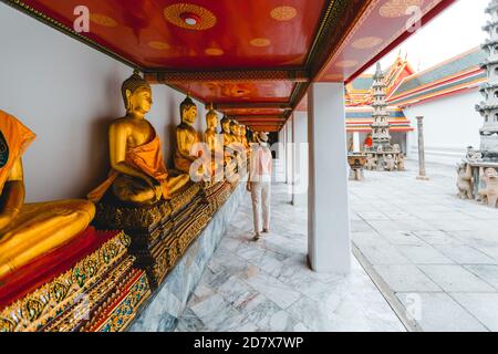 La donna paga rispetto al Buddha d'oro del carico, Wat Pho a Bangkok, Thailandia Foto Stock