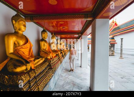 La donna paga rispetto al Buddha d'oro del carico, Wat Pho a Bangkok, Thailandia Foto Stock