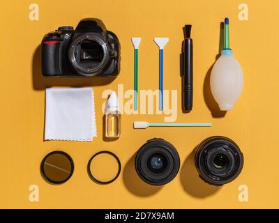 Fotocamera DSLR, obiettivi, filtri, tamponi, pulitore per sensori, soffiatore d'aria, microfibra e pennarello con lenti a filo giallo. Set di pulizia per apparecchiature fotografiche. Foto Stock