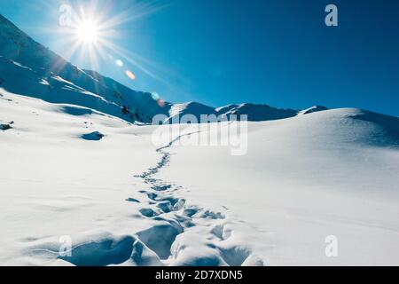 Orme nel paesaggio delle montagne innevate. Bellissima alba invernale. Avventura e tempo di viaggio Foto Stock