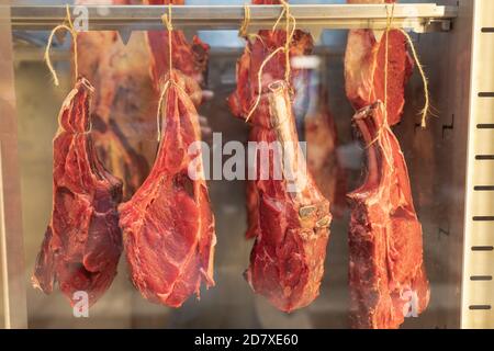 carne cruda fresca sull'osso appesa ad una corda in una vetrina Foto Stock