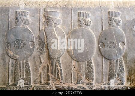 Antico muro con bassorilievo con guerrieri assiri con lance e scudi, Persepolis, Iran. Sito patrimonio dell'umanità dell'UNESCO Foto Stock