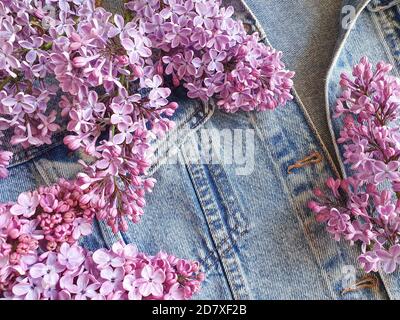 Fiori lilla su sfondo denim. Carino ed elegante mockup foto marcare a caldo con fiori. Piatto floreale, vista dall'alto, sfondo prodotto primavera. Foto Stock