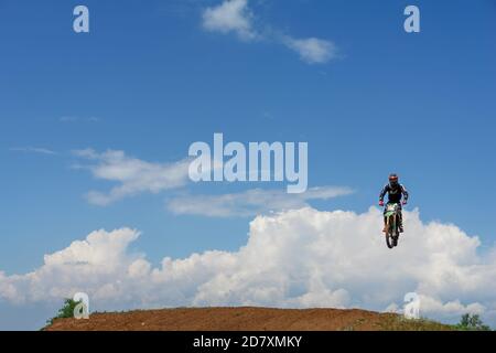 Moto in volo contro il cielo blu. Il pilota fa un salto. Salto di un motociclista Foto Stock