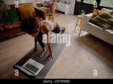 Visualizzazione ad alto angolo di una donna che guarda i video sul computer portatile mentre esercitarsi sul tappeto di yoga a casa Foto Stock