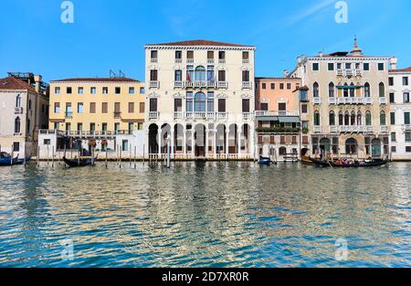 Il gondoliere prende i turisti sulla sua gondola sul Canal Grande passando davanti a edifici storici. I turisti tornano a Venezia, ma molto meno che negli ultimi anni. Foto Stock