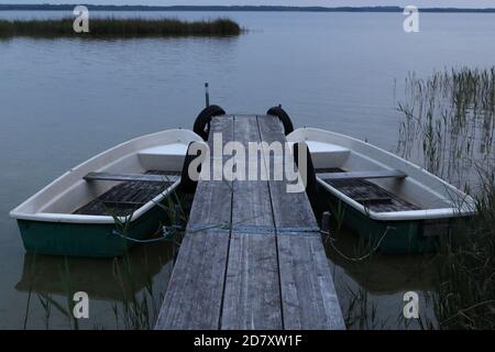 Due barche a remi su un molo di legno, il lago Kölpinsee, il distretto dei laghi di Mecklenburg, Meclemburgo-Vorpommern, Germania Foto Stock