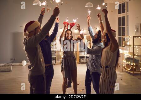 Giovani amici o colleghi con sparklers che si augurano Merry Natale e Felice anno nuovo Foto Stock