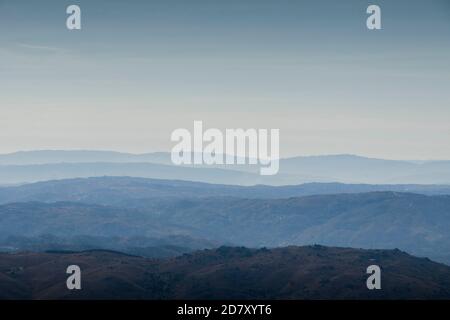 Le forme e le curve delle montagne svaniscono nell'orizzonte sottostante la nebbia mattutina Foto Stock