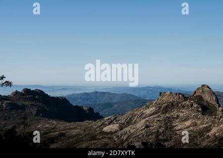 Le forme e le curve delle montagne svaniscono nell'orizzonte sottostante la nebbia mattutina Foto Stock