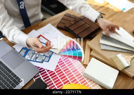 Mani maschili sopra la tabella su cui sono localizzati campioni di materiali di finitura e schemi di colore. Foto Stock