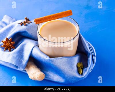Tè Masala chai. Bevanda indiana tradizionale - tè masala con varie spezie. Bicchiere di tè masala su sfondo blu Foto Stock