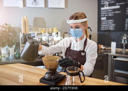 Cameriere giovane che mostra modi alternativi di preparare il caffè Foto Stock