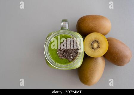 Frullato kiwi con chia in vasetto di muratore su sfondo grigio con cibo kiwis.Healthy, concetto di dieta con spinaci, ananas, kiwi e uva. Foto Stock