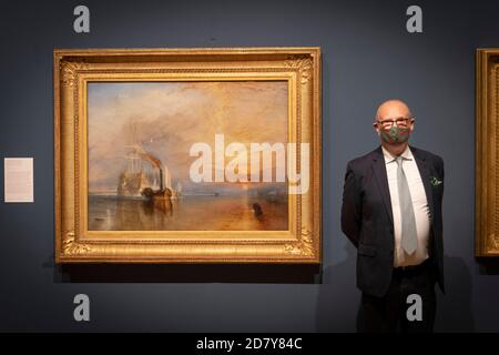 Londra, Inghilterra. 26 ottobre 2020. David Blayney Brown, curatore senior di Tate Britain accanto al dipinto su tela The Fighting Temeraire di Turner alla rassegna stampa di un’importante mostra, Turner’s Modern World, Apertura alla Tate Britain il 28 ottobre 2020 dedicata a JMW Turner (1775-1851), Turner’s Modern World rivela come il pittore paesaggista britannico abbia trovato nuovi modi per catturare gli eventi quotidiani, dall’impatto della tecnologia sul mondo naturale agli effetti della modernizzazione sulla società. (Foto di Sam Mellish / Alamy Live News) Foto Stock