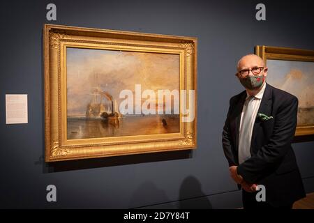 Londra, Inghilterra. 26 ottobre 2020. David Blayney Brown, curatore senior di Tate Britain accanto al dipinto su tela The Fighting Temeraire di Turner alla rassegna stampa di un’importante mostra, Turner’s Modern World, Apertura alla Tate Britain il 28 ottobre 2020 dedicata a JMW Turner (1775-1851), Turner’s Modern World rivela come il pittore paesaggista britannico abbia trovato nuovi modi per catturare gli eventi quotidiani, dall’impatto della tecnologia sul mondo naturale agli effetti della modernizzazione sulla società. (Foto di Sam Mellish / Alamy Live News) Foto Stock