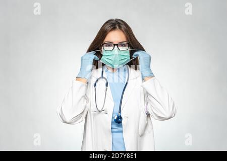 Giovane medico sicuro in camice bianco, guanti di protezione in lattice con maschera medica. Donna in guanti medici indossare una maschera protettiva. Coronavirus Foto Stock