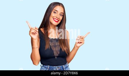 Giovane donna ispanica che indossa abiti casual sorridente sicuro puntando con le dita a diverse direzioni. Copy spazio per la pubblicità Foto Stock