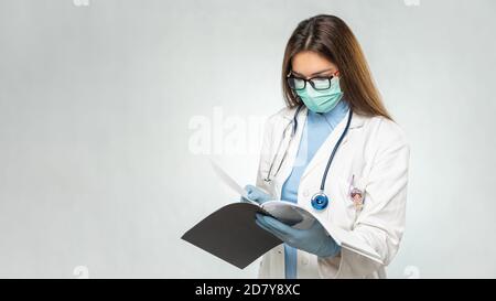 Giovane donna caucasica medico di lettura documenti. Cartella clinica. Foto Stock