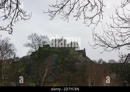 Casta di Edimburgo in Scozia in cima al davanzale visto dal basso e circondato da brancate di alberi in un giorno grigio e nuvoloso. Foto Stock