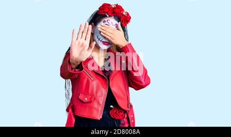 Donna che indossa giorno del costume morto su sfondo coprendo gli occhi con le mani e facendo gesto di stop con espressione triste e paura. Imbarazzato e ne Foto Stock