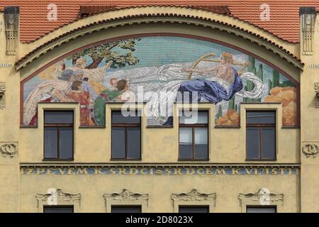 Allegoria di musica raffigurata nel mosaico in maiolica progettato dal pittore ceco Karel Ludvík Klusáček sulla Casa della Società del coro di Hlahol sull'argine del fiume Moldava a Nové Město (Città Nuova) a Praga, Repubblica Ceca. L'edificio in stile liberty, progettato dagli architetti cechi František Schlaffer e Josef Fanta con decorazioni in stucco dello scultore ceco Josef Pekárek, è stato costruito dal 1902 al 1905 in quello che oggi è conosciuto come Masarykovo Embankment. Foto Stock