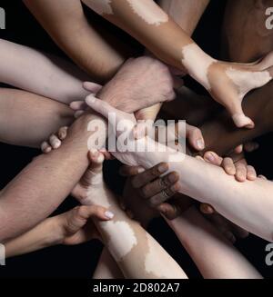 Supporto. Mani di persone diverse in contatto isolate su sfondo nero studio. Concetto di relazione, diversità, inclusione, comunità, togetherness. Contatto forte e duro, creando un'unità. Foto Stock