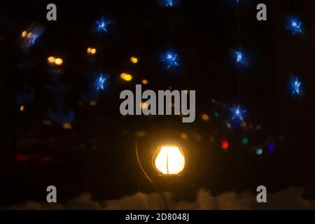 Lanterna natalizia che illumina su un davanzale con stella blu garland sopra di notte Foto Stock