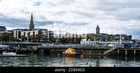 Il paesaggio urbano di Dun Laoghaire, Dublino, Irlanda con la Lifeboat RNLI a prua e le torri della chiesa e la città sullo sfondo. Foto Stock