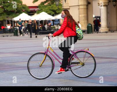 Cracovia. Cracovia. Polonia. Giovane donna che cavalcano una bicicletta che indossa una maschera. Foto Stock