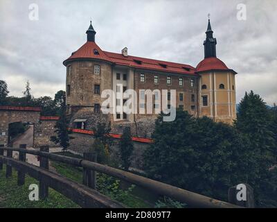 Una vista pittoresca del tetto rosso del castello di Škofja Loka contro il cielo nuvoloso dell'autunno. Foto Stock