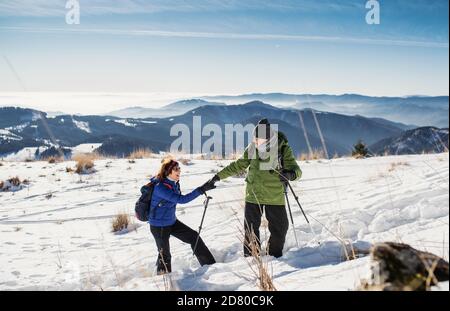 Coppia senior con bastoni nordici escursionistici nella natura innevata invernale. Foto Stock