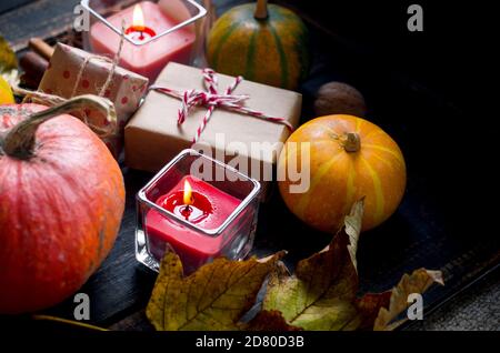 composizione autunnale con candele, zucche e foglie autunnali, tazza di tè su tavola di legno. Foto Stock